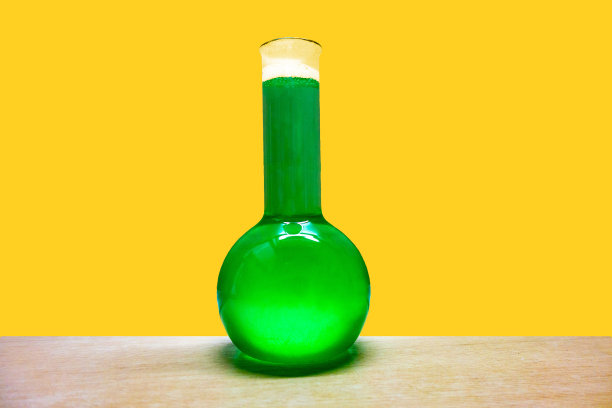 化学蒸馏玻璃瓶与有毒的绿色液体在黄色的墙壁背景图片下载