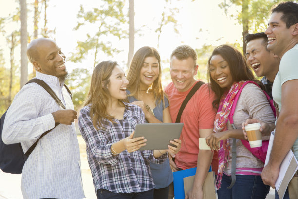 大学生朋友们在大学校园里分享电子平板电脑。素材图片