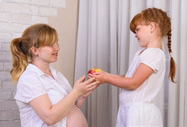 红头发的小女孩给怀孕的妈妈一个苹果图片下载