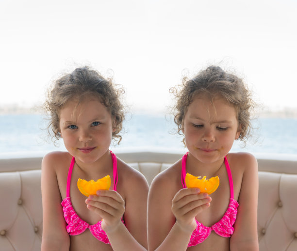 儿童橘子。快乐的小女孩们在海边吃橘子。照片拼贴。图片下载