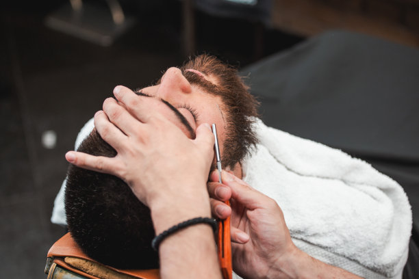 胡须造型和修剪。近距离裁剪的照片造型的胡子。太时髦了!广告和理发店概念。剃刀在专业理发师手中图片下载