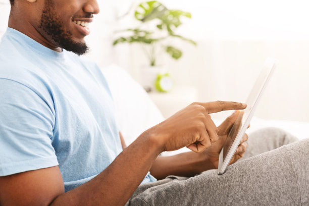 轻松随意的男人在床上用平板电脑图片下载