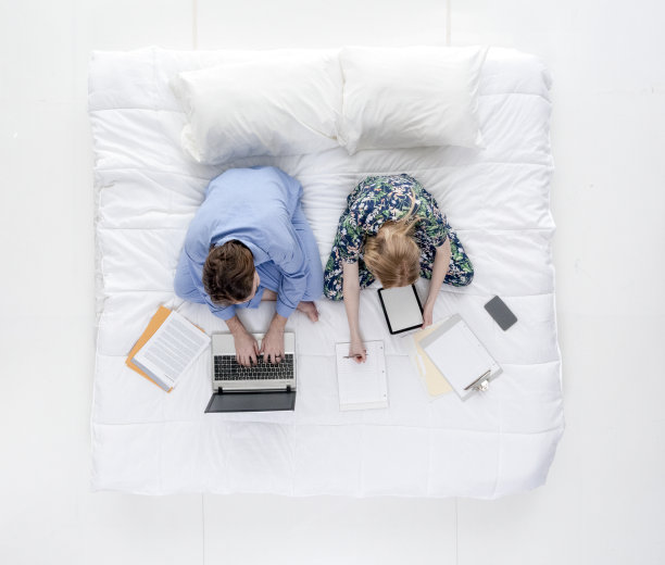 一对夫妇坐在床上工作图片下载