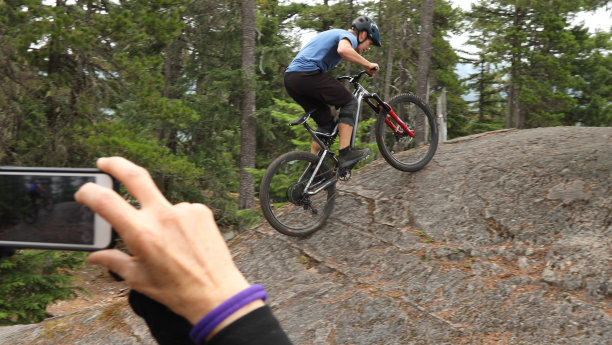 看过去的女人拍摄山地车攀登陡峭的岩石板图片下载