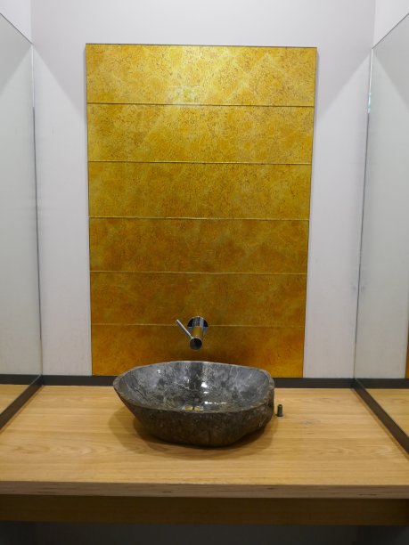 灰色的天然石材脸盆放在木质脸盆架上，前面是金色闪亮的纹理墙面和白色的背景图片下载