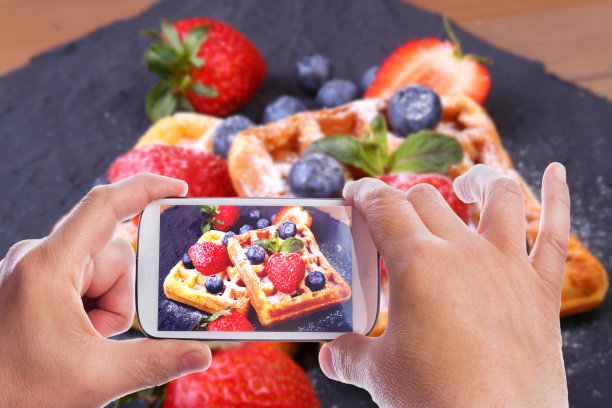 自制传统比利时华夫饼，用新鲜水果、浆果和糖粉放在黑色盘子里。平铺，俯视图，拷贝空间。图片下载