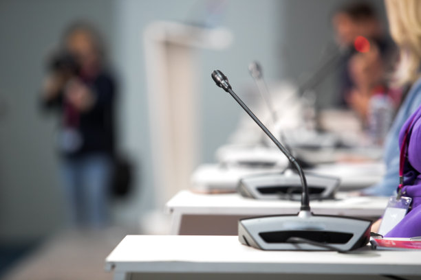 在音乐厅或会议室的麦克风柔和和模糊风格的背景。麦克风上方是会场或会议室背景的抽象模糊照片。图片下载