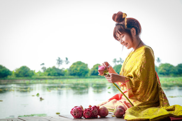 穿着泰国衣服的女人，在泳池边折着花图片下载