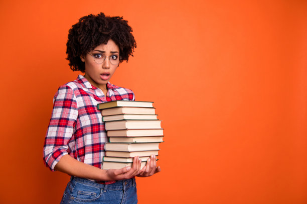 近的侧面侧面照片美丽的她，她的模特女士，难以置信的张开的嘴，手臂，手，许多书，意外的考试，穿休闲的格子衬衫孤立明亮的橙色背景图片下载