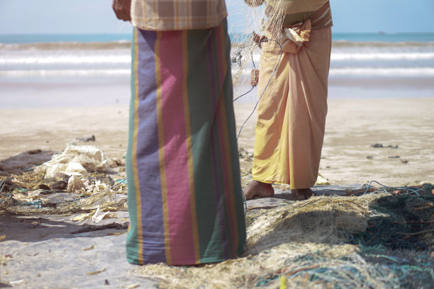 赤脚躺在印度洋海岸的垃圾堆里。塑料和聚乙烯造成的生态灾难。库存图片图片下载