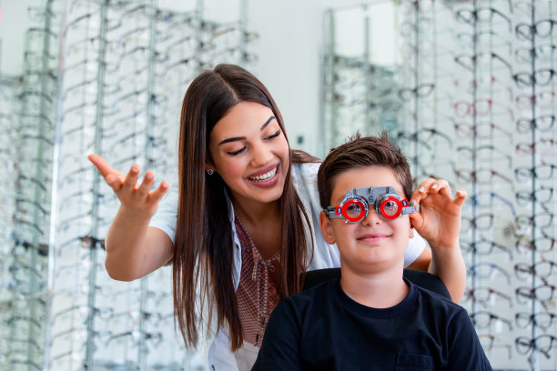 迷人的眼科医生检查年轻男孩与验光师试验框架。儿童患者到眼科门诊检查视力图片下载