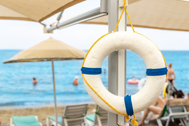 美丽的白色救生圈挂在伞上热带沙滩。救生圈与美丽的蓝色海岸异国度假胜地。旅游度假概念图片下载