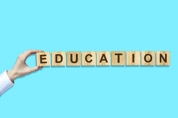 教育的概念。女性的手用木块上的字母组成单词。蓝色背景。孤立。图片下载