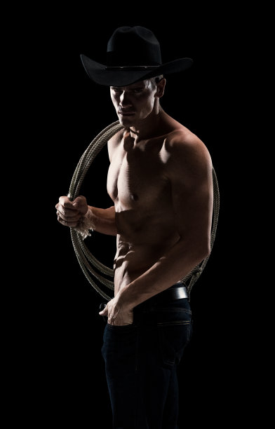 身穿衬衣、头戴牛仔帽、手拿套索、身穿牛仔裤的帅气男子图片下载