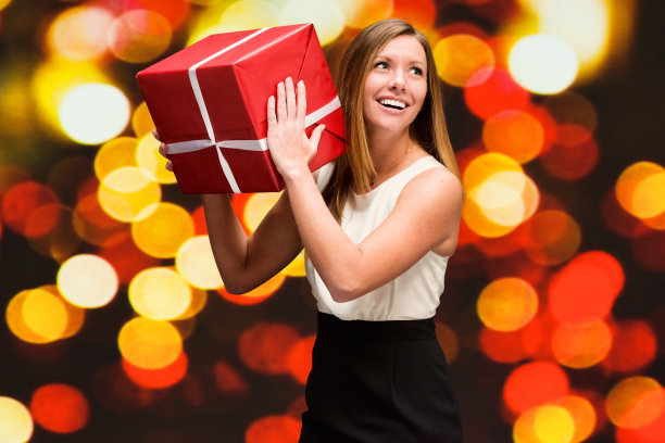 美丽的女人在散景背景拿着礼盒图片下载