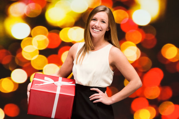美丽的女人在散景背景拿着礼盒图片下载