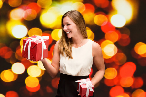 美丽的女人在散景背景拿着礼盒图片下载