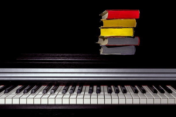 黑色背景的钢琴上有一堆彩色的书图片下载