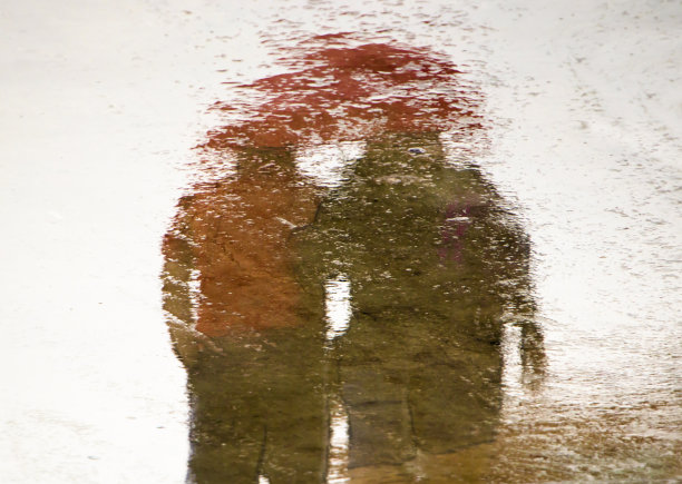 模糊的倒影剪影在水坑的夫妇牵着手图片下载