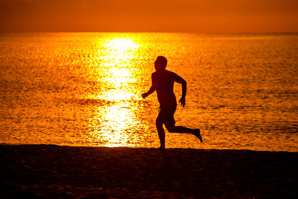清晨日出时在海滩上跑步的人图片下载