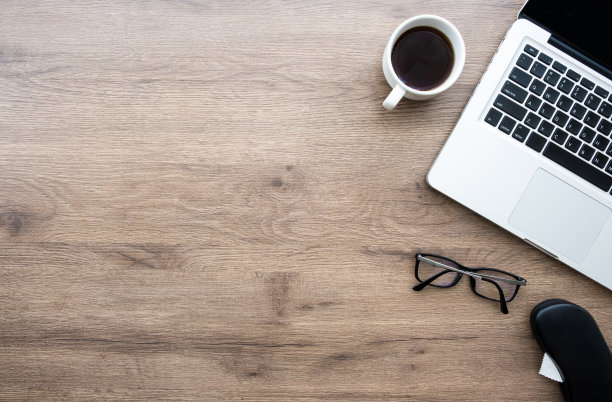 木制办公桌，桌上有笔记本电脑，一杯咖啡和用品。顶视图与复制空间，平放。图片下载