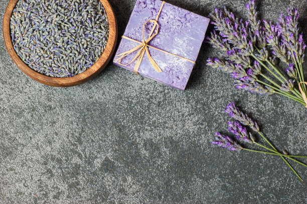 薰衣草天然肥皂与新鲜的薰衣草花和干燥的薰衣草种子在灰色的乡村桌子上，香薰水疗按摩概念图片下载
