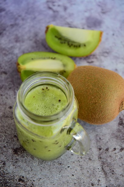 在灰色背景的一个罐子里的新鲜猕猴桃汁图片下载