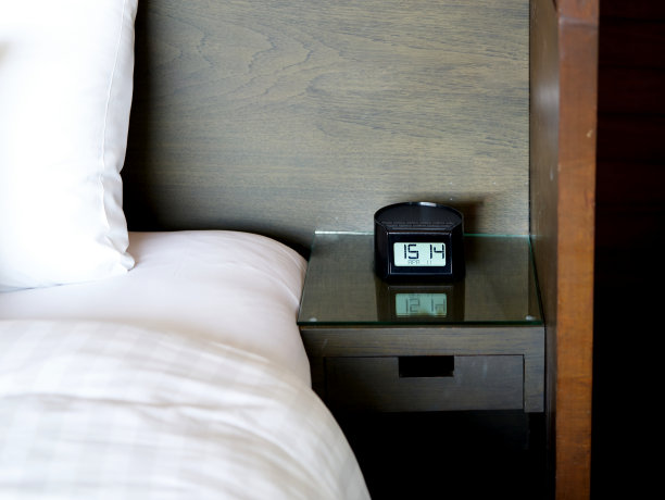 酒店桌上床上的闹钟在旅行时间的概念图片下载