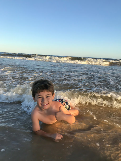 男孩在海滩上玩海浪图片下载