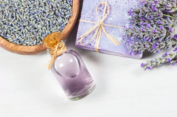薰衣草天然肥皂和薰衣草油与新鲜的薰衣草花和干燥的薰衣草种子在白色的乡村桌子图片下载