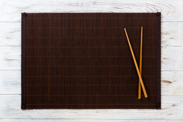 两根寿司筷子与空竹席或木板在白色木制背景顶视图与复制空间。空洞的亚洲食物背景图片下载