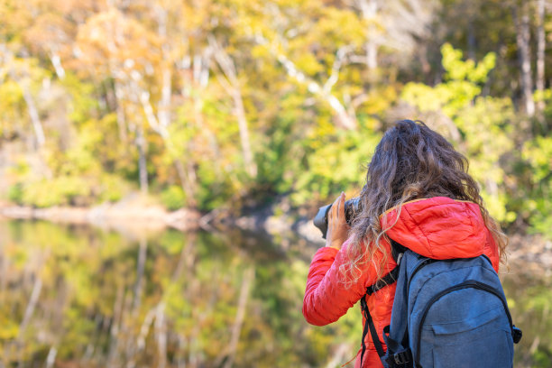 年轻女子摄影师背包和相机拍照，拍摄大瀑布秋天的树叶与河的倒影在马里兰州图片下载
