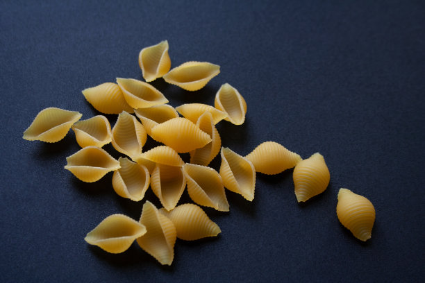 黑色背景上的生贝壳意面图片下载