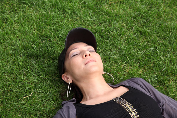年轻的白人妇女躺在绿色的草地上图片下载