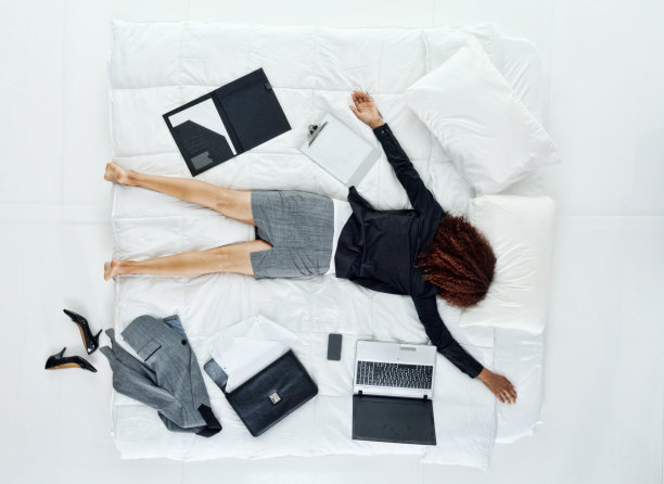 非洲裔美国妇女与黑色卷发穿着一套在床上谁是工作到很晚，是疲倦图片下载