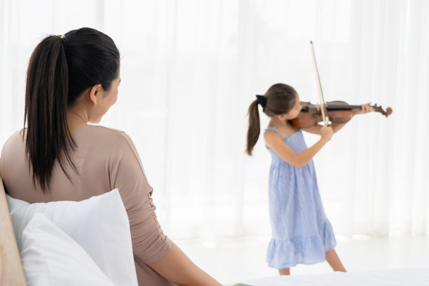 女儿拉小提琴给她妈妈听。图片下载