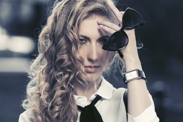 年轻时尚的金发商务女人戴着太阳镜走在城市的街道上图片下载