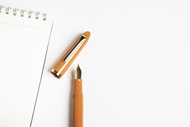 橙色钢笔和螺旋装订笔记本图片下载