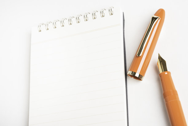 橙色钢笔和螺旋装订笔记本图片下载
