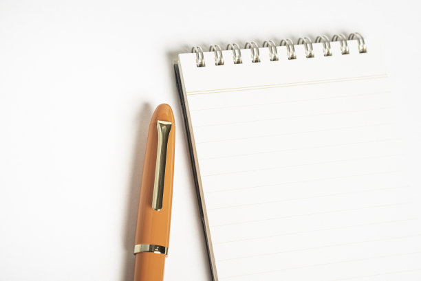 橙色钢笔和螺旋装订笔记本图片下载