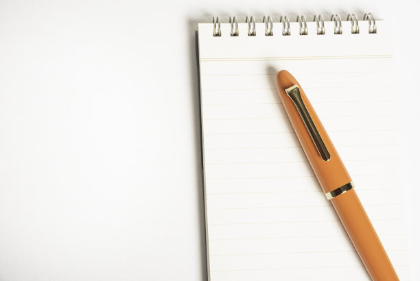 橙色钢笔和螺旋装订笔记本图片下载