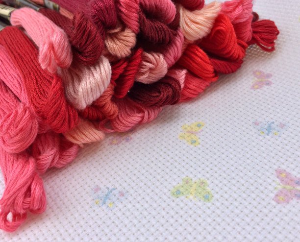 彩色的牙线。红色的阴影。宏观纹理织物帆布与蝴蝶的背景。针线、缝纫线和十字绣线。图片下载