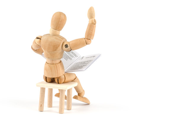 木制人体模型对着什么东西读一本书，并用手势讲述故事图片下载