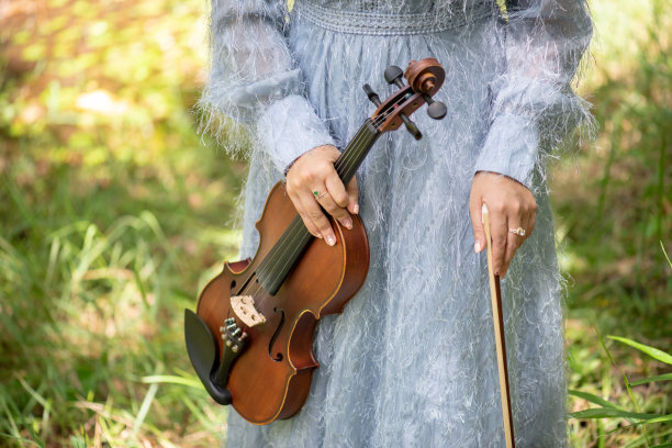 孤独的小女孩拿着小提琴在森林迷人的风景图片下载