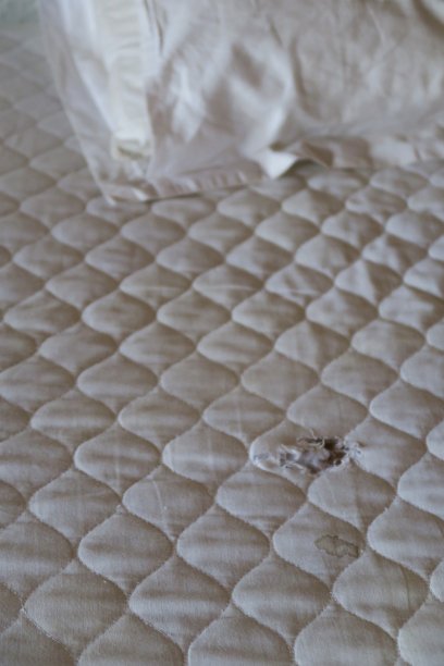 肮脏的酒店床的图片，撕破的旧床垫和白色污渍的枕头照片图片下载