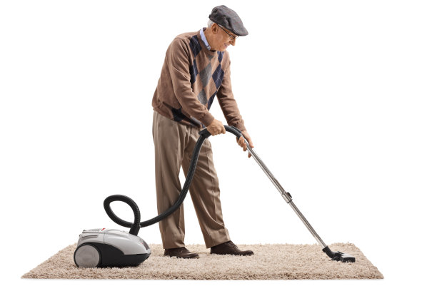 一位老人正在用吸尘器吸地毯图片下载