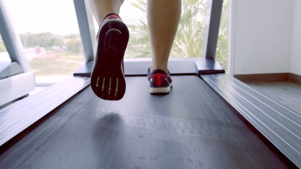 靠近鞋子，男人肌肉发达的腿，脚在跑步机上跑步，在健身馆锻炼。图片下载