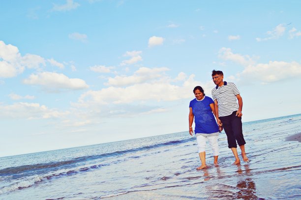 这是一对上了年纪的亚洲印度夫妇在海边沙滩上散步的浪漫照片图片下载