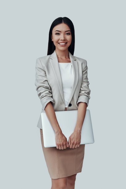 t和聪明。迷人的年轻亚洲女子看着相机和微笑，而站在灰色的背景图片下载