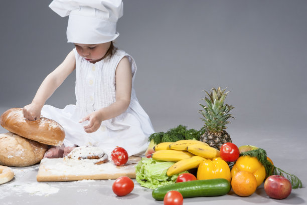 可爱有趣的白人女性厨师与许多蔬菜在前面。在灰色的背景下。水平的作文图片下载